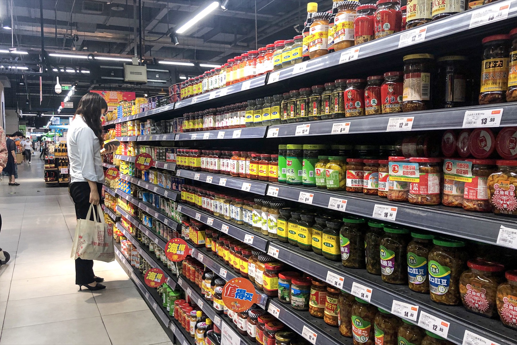北京のスーパーで商品を見比べる買い物客
