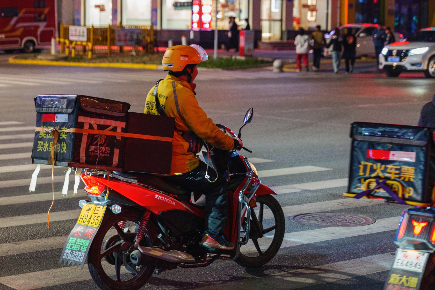 中国の都市部で信号待ちをする美団の配達員